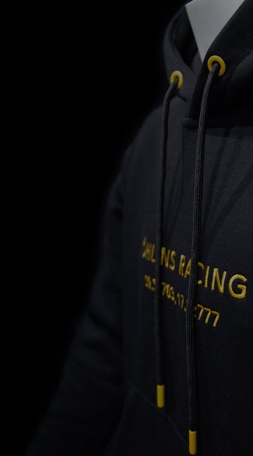 Öhlins merchandise: black hoodie with yellow embroidered 'Öhlins Racing' text.
